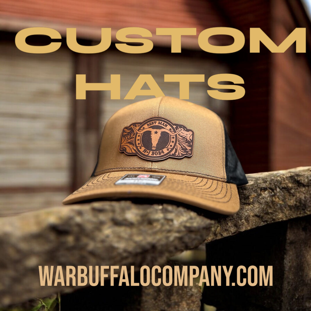 Tan and black trucker hat with 'Best Man' buffalo logo, text above reads 'Custom Hats,' with 'warbuffalocompany.com' below.